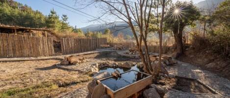 A rustic outdoor setting with a wooden trough, rocks, and a wooden fence.
