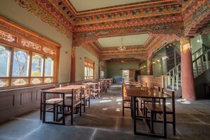 Een klassiek interieur met rijen tafels en stoelen, grote ramen en ingewikkelde plafonddecoraties.