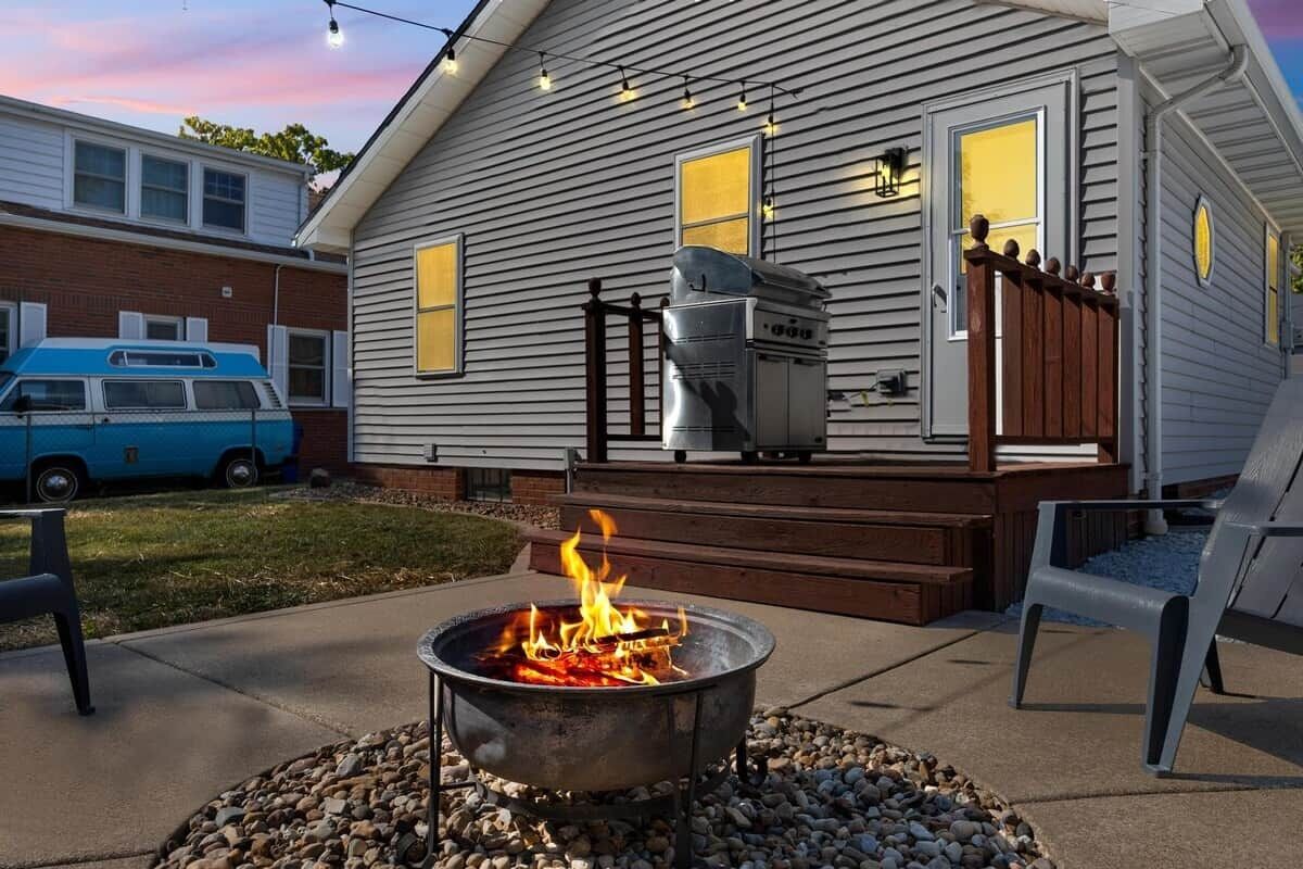 A residential outdoor area with a fire pit, a barbecue grill, and a deck.
