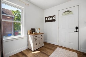 A room with a white door, a wooden dresser, a window, and a wall-mounted decoration. - Play & Stay in the Heights! (Peoria Heights)