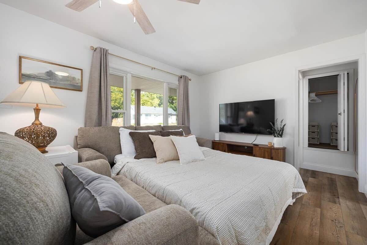 Un dormitorio con cama, sofá, televisor y armario.