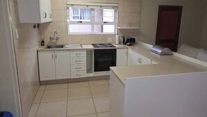 Una cocina compacta con armarios blancos, una ventana sobre el fregadero y un microondas en la encimera.