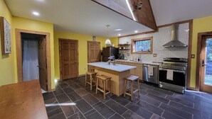 Una cocina con una isla central, taburetes de madera, horno empotrado y una ventana sobre el fregadero.