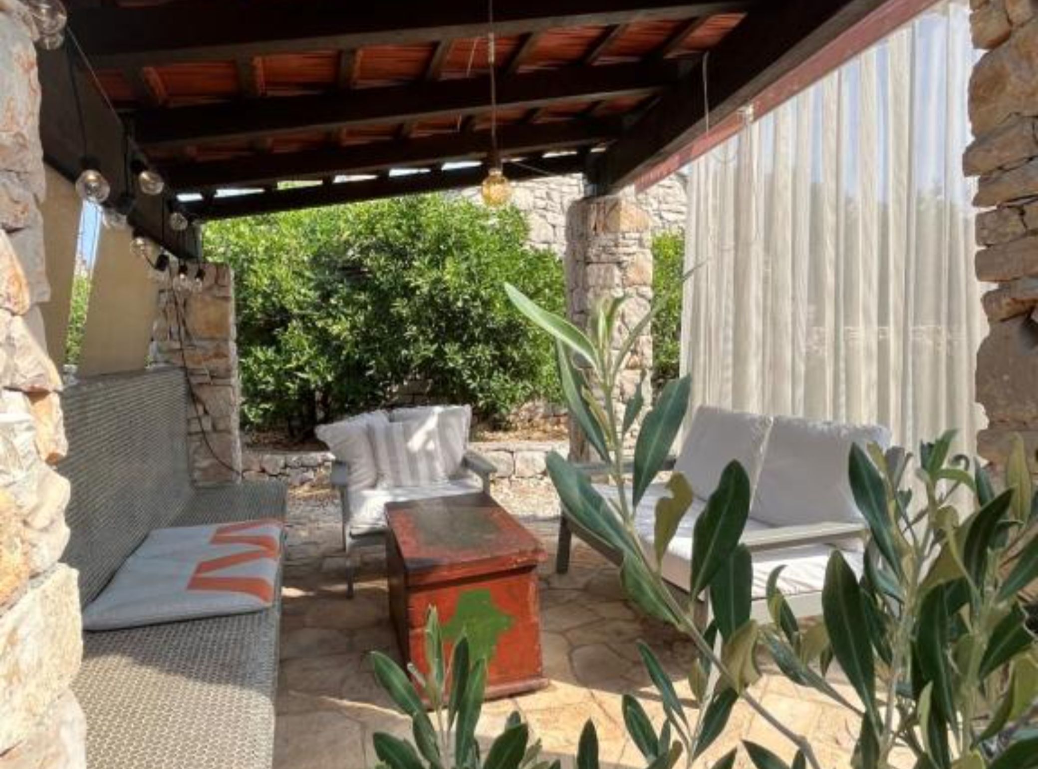Eine Terrasse im Freien mit Steinmauern, einem überdachten Sitzbereich und einem Holztisch.