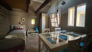 A cozy attic bedroom with a glass dining table, a bed, and a small window. - Romantic Stone House and Yard Near Stunning Beach (Trogir)