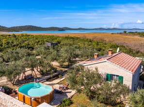 A villa with a swimming pool, surrounded by olive trees and a view of a lake.