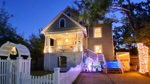 A two-story house with a porch, a small staircase, and a white picket fence.