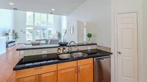 A modern kitchen with a black countertop, stainless steel sink, and wooden cabinets. - Stylish Houston Getaway (Houston)