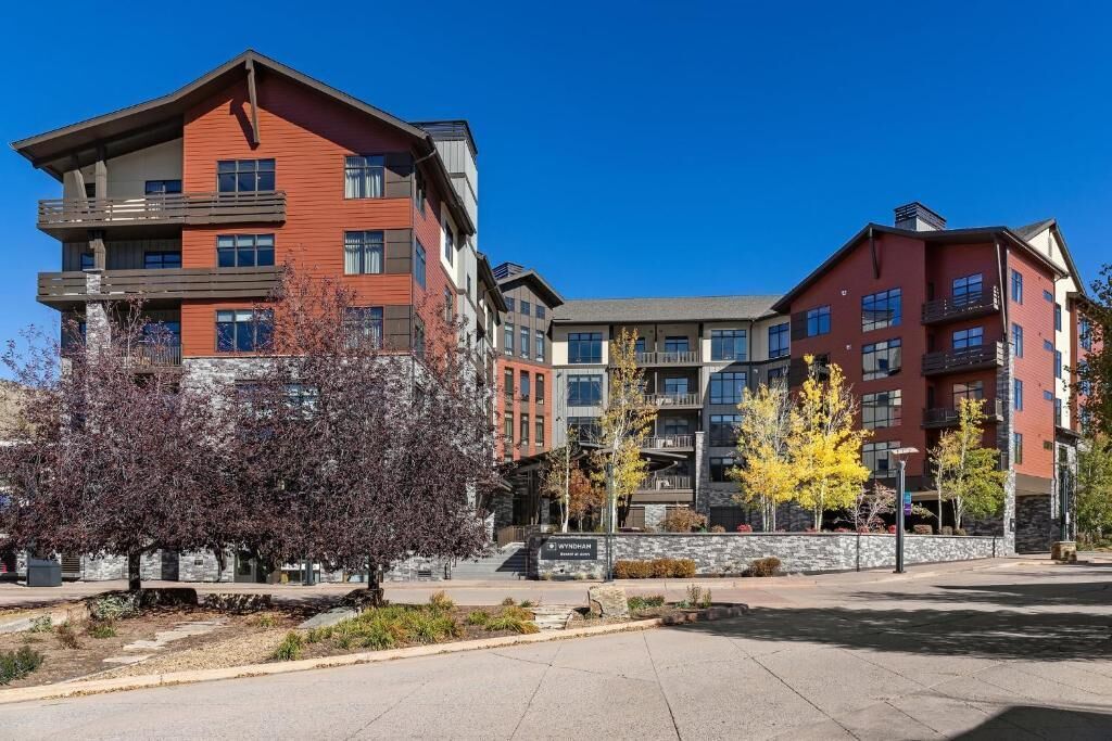 A multi-story building with a mix of red and grey exterior walls, balconies, and a stone base.