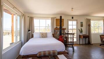 Quarto espaçoso com uma cama grande, lareira, escrivaninha e vista para o exterior.