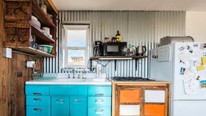 Una cocina con armarios azules, un refrigerador blanco y una ventana con vista a un edificio.