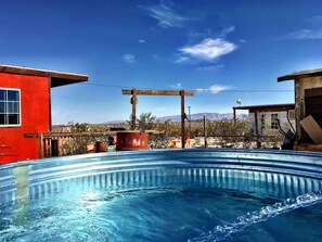 A swimming pool with a wooden pergola and a red building in the background.
