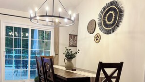 A dining area with a wooden table, dark wooden chairs, a chandelier, and wall art. - New & Cozy 5 BR Lake Anna Retreat - Large Game Room & Lake Access (Bumpass)