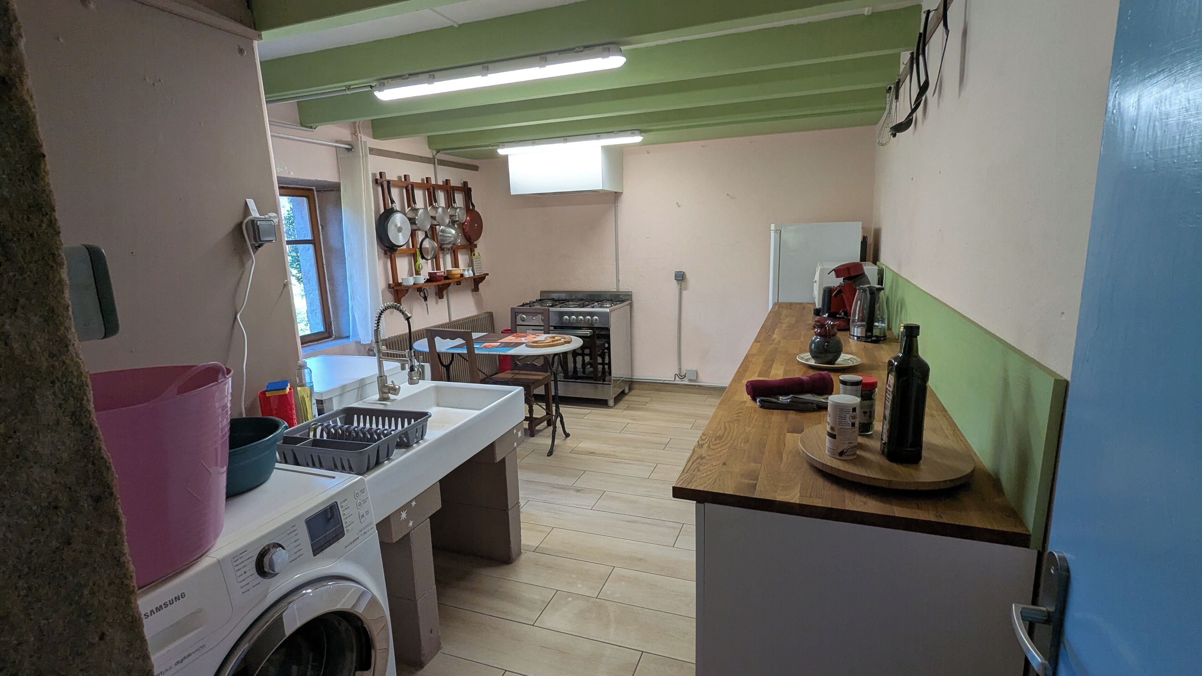 A compact kitchen with a washing machine, a sink, a stove, and a dining area.
