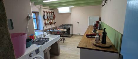 A compact kitchen with a washing machine, a sink, a stove, and a dining area.