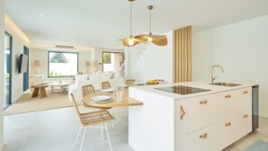 A modern kitchen with a central island, white cabinetry, and a dining area with wicker chairs. - Empress Villa Tropical Garden (Funchal)