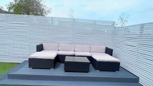 Un canapé modulable avec des coussins et une table basse, le tout installé sur une plateforme surélevée dans un espace extérieur.