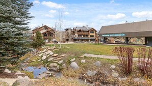A lodge with a stone pathway leading to a building, surrounded by trees and a small stream. - Arrowhead at Beaver Creek, Direct Ski Access & A/C (Edwards)