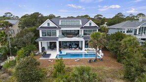 A two-story house with a large front yard, a swimming pool, and a patio area with outdoor furniture. - Ultra-Luxury Oceanfront Palmetto Dunes Escape with Private Pool & Hot Tub (Hilton Head Island)