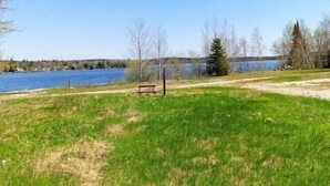 A grassy area with a bench and a lake in the background. - Restful stay at Obaska (Senneterre)
