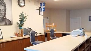 A reception area with a long counter, two chairs, a clock, a framed Buddha statue, and a potted plant. - Restful stay at Obaska (Senneterre)