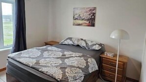 Ein Schlafzimmer mit einem Bett, einem Nachttisch, einer Lampe und einem Gemälde an der Wand.