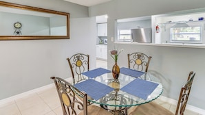 A dining area with a glass table, metal chairs, and blue placemats. - Fort Pierce Getaway: Near Marina Sq & Downtown! (Fort Pierce)