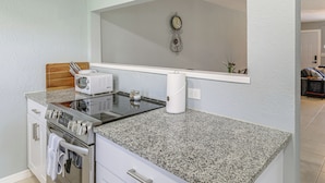 A kitchen with granite countertops, a microwave, an oven, and a wall-mounted clock. - Fort Pierce Getaway: Near Marina Sq & Downtown! (Fort Pierce)