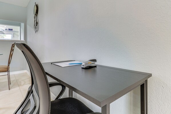 A small, modern office space with a dark wooden desk, a chair, and a wall-mounted clock. - Fort Pierce Getaway: Near Marina Sq & Downtown! (Fort Pierce)