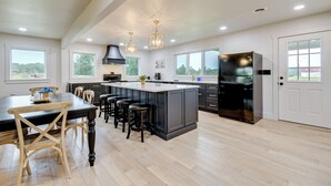 A modern kitchen with a large island, dark cabinetry, and a black refrigerator. - 10 Mi to Red River Gorge: Peaceful Rural Getaway! (Campton)