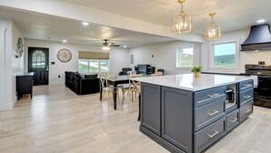 A spacious kitchen with a large island, dark cabinetry, and modern lighting fixtures. - 10 Mi to Red River Gorge: Peaceful Rural Getaway! (Campton)