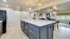 A modern kitchen with a large island, dark cabinetry, and gold fixtures. - 10 Mi to Red River Gorge: Peaceful Rural Getaway! (Campton)