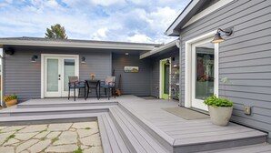 Ein graues Haus mit überdachter Terrasse, einer Tür und einem Fenster.