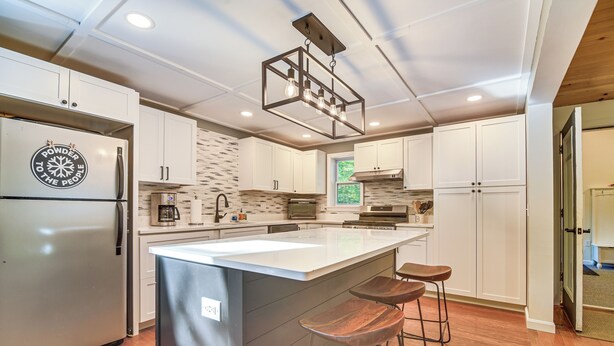 Une cuisine moderne dotée d’un grand îlot central, de meubles blancs et d’un réfrigérateur en acier inoxydable.