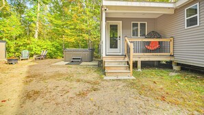 Une petite cabane dotée d’une véranda, d’un bain à remous et d’une terrasse avec des sièges d’extérieur.