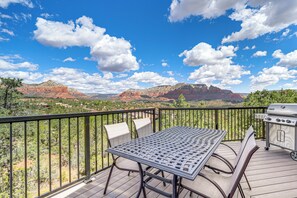 Una terrazza con tavolo e sedie, un barbecue e una vista panoramica su formazioni rocciose rosse.