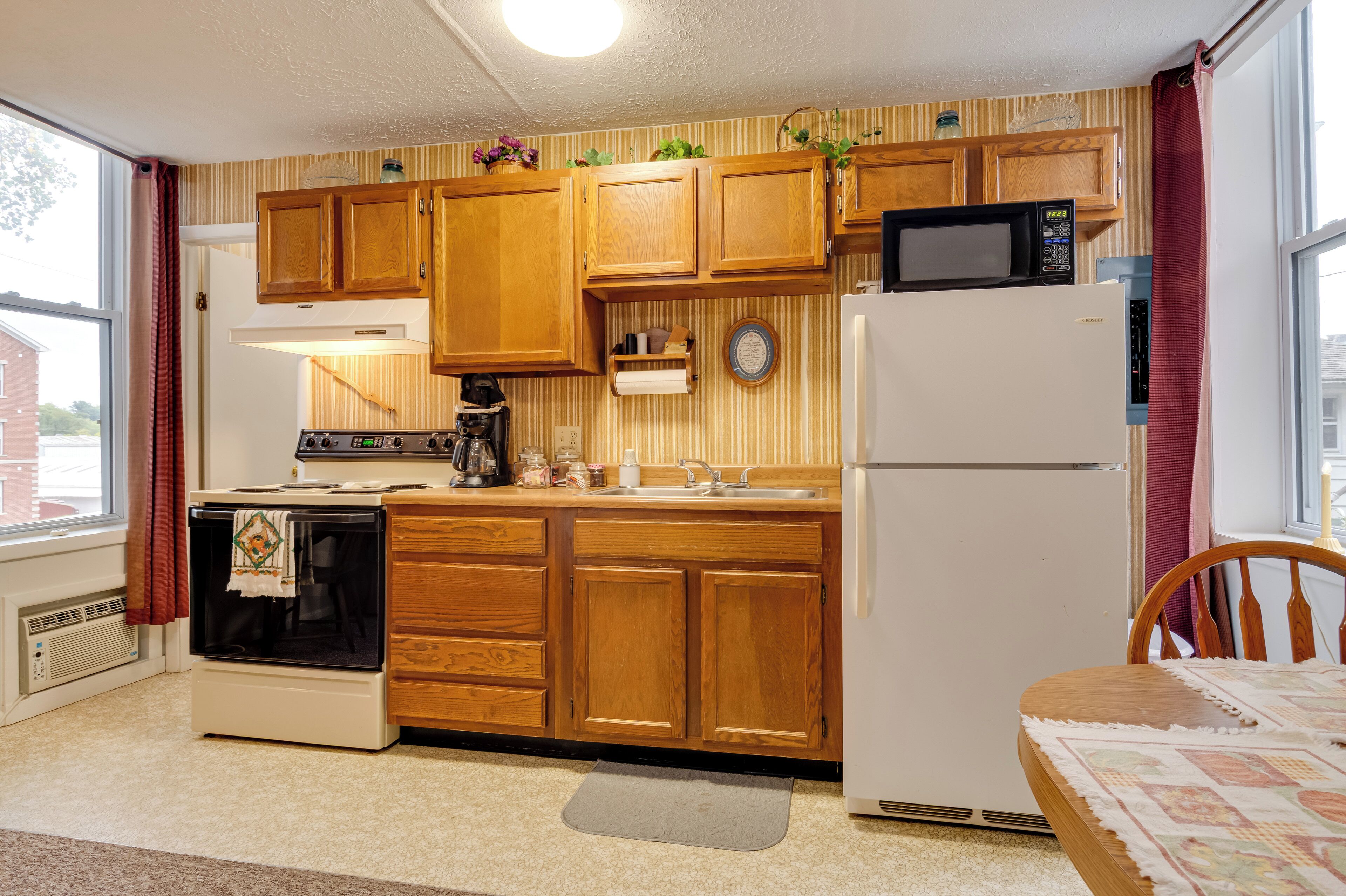Une cuisine avec des meubles de rangement en bois, une cuisinière, un four à micro-ondes et un réfrigérateur.