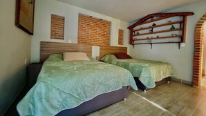 A bedroom with two beds, a brick wall, and a wooden shelf unit. - Mexican style house in the heart of the magical town of San Andres Cholula. (San Andrés Cholula)