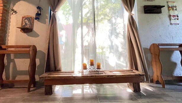 A room with a wooden bench, a window with sheer curtains, and a small table with candles. - Mexican style house in the heart of the magical town of San Andres Cholula. (San Andrés Cholula)