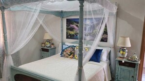 A four-poster canopy bed with a white bedspread and multiple pillows. There are two bedside tables with lamps and decorative items. - Giordano Rooms Amalfi Coast  (Tramonti)