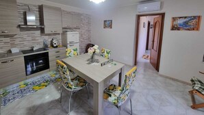 A modern kitchen with a dining table, chairs, and a refrigerator. - Giordano Rooms Amalfi Coast  (Tramonti)