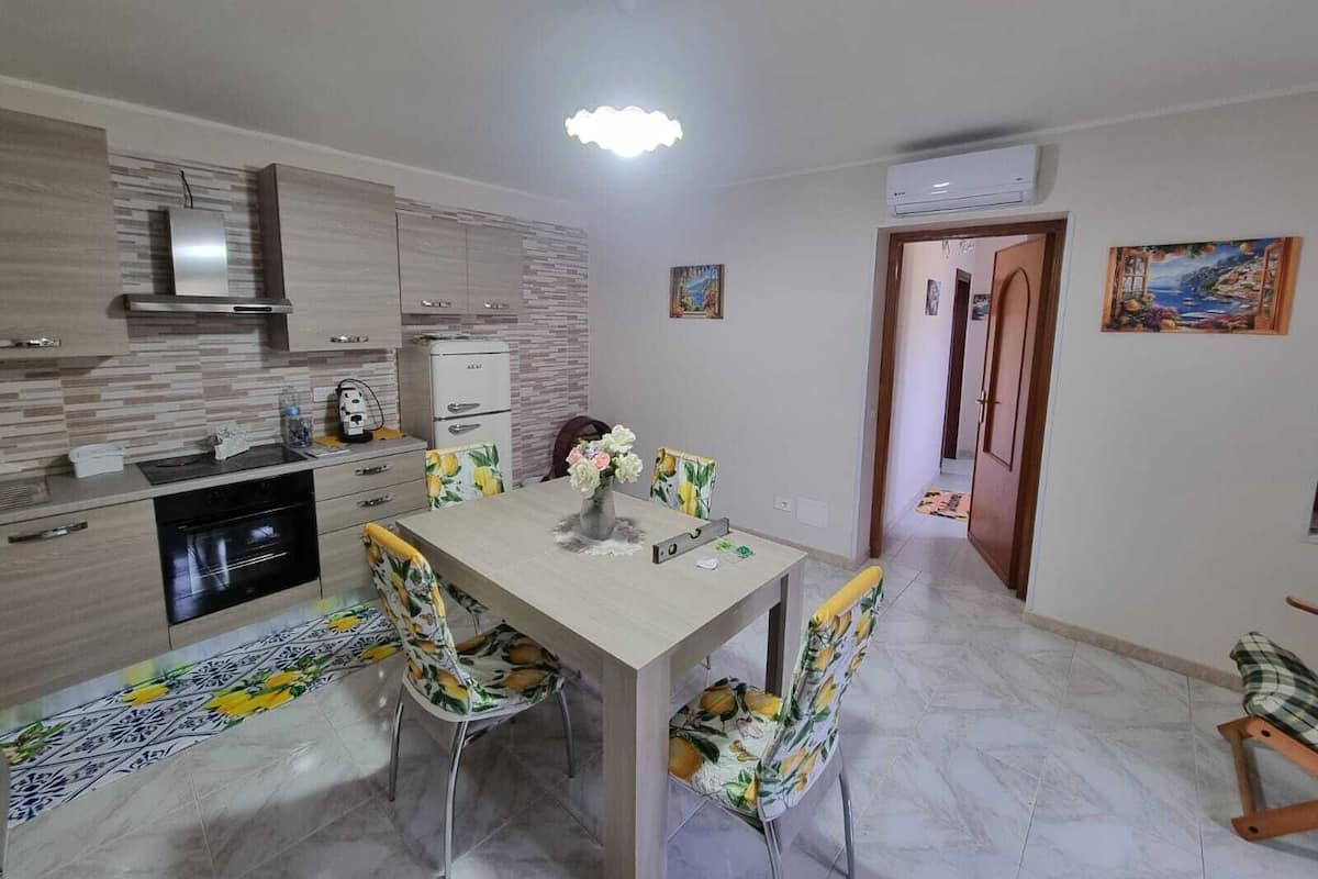 A modern kitchen with a dining table, chairs, and a refrigerator.