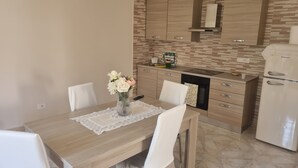 A modern kitchen with wooden cabinets, a dining table with chairs, and a vase with flowers. - Giordano Rooms Amalfi Coast  (Tramonti)