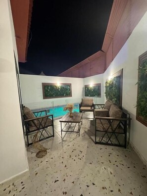 An outdoor seating area with a pool view, featuring a table and two sofas. - Golden Hotel Chalets (Madinah)