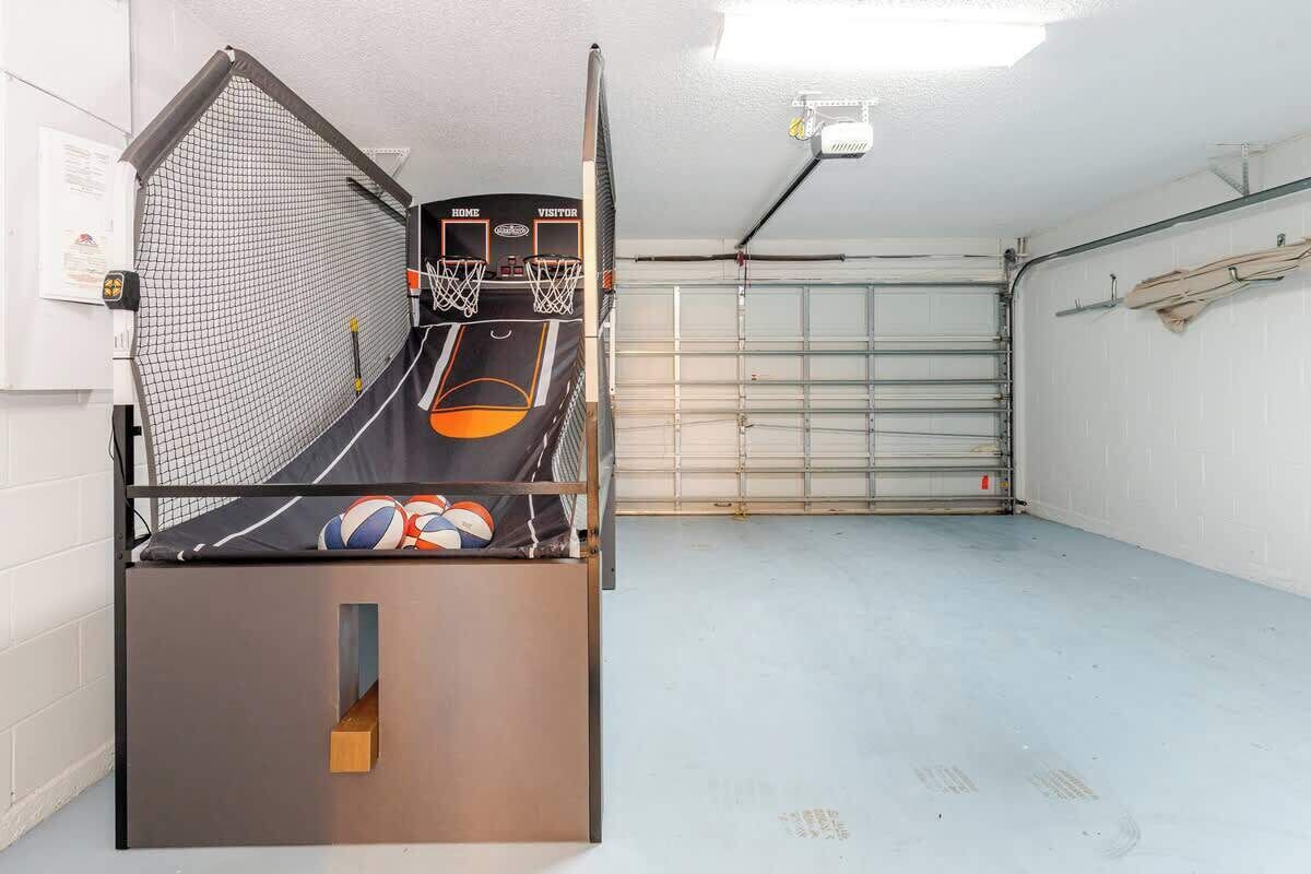 A basketball court with a net, two basketball hoops, and a bench with sports balls.