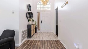 Ein Flur mit Holzboden, einer weißen Tür, einem schwarzen Stuhl und einer Wand mit runden Spiegeln.