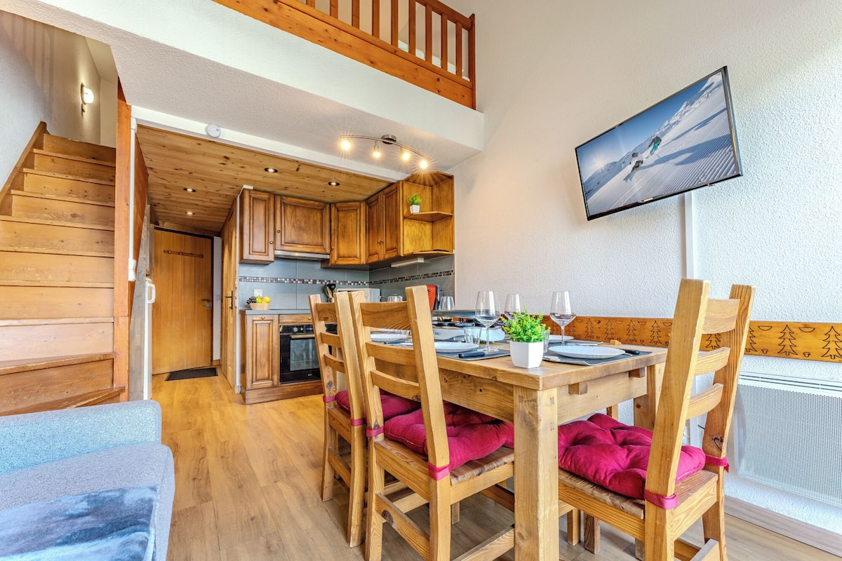 L’intérieur est en bois et comprend une table à manger pour quatre personnes, des chaises en bois, un coin cuisine et un téléviseur fixé au mur.