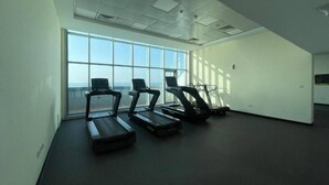 Un gimnasio con cintas de correr y un amplio ventanal con vistas.
