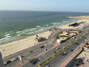 Eine Küstenstraße mit Strand auf einer Seite und einem Kreisverkehr mit Palmen.