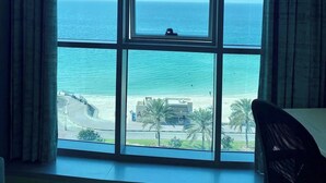 A room with a large window overlooking a beach and the sea.
